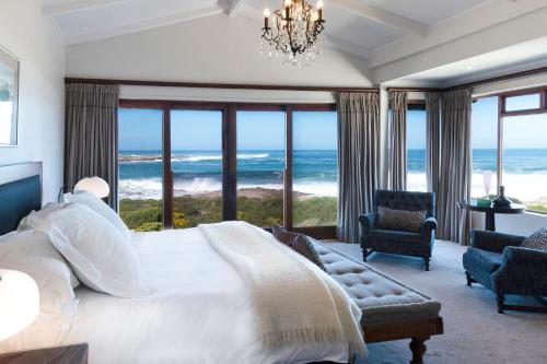 a bedroom with a bed and views of the ocean at Schulphoek Seafront House in Hermanus