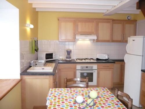 une cuisine avec une table et un réfrigérateur blanc dans l'établissement Charmant gîte 3 chambres avec jardin, proche activités neige et randonnées, animaux acceptés ! - FR-1-496-199, à La Chambonie