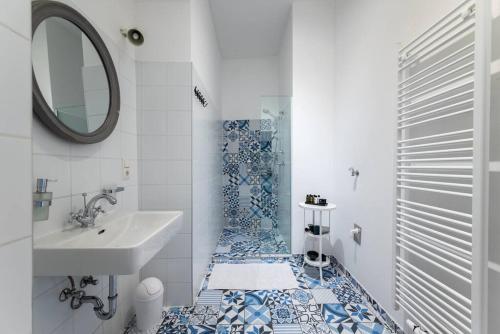ein blau-weißes Bad mit einem Waschbecken und einem Spiegel in der Unterkunft HM • Chic Studio Near Metro & Center in Wien