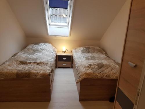 two beds in a small room with a window at Ferienwohnung Schäfer Deichgraf in Burhave