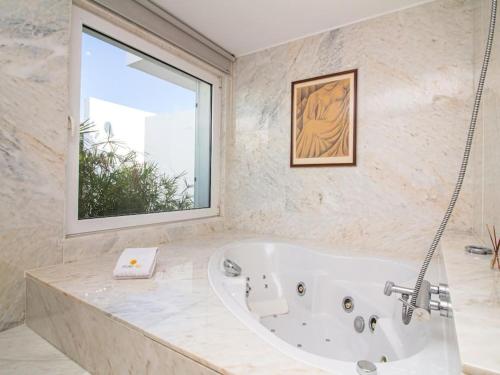 a bath tub in a bathroom with a window at Laguna 25 House - Privat Pool & Games Room & Gym & Jacuzzi in Quarteira