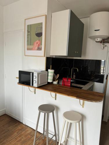 une cuisine avec un comptoir avec des tabourets et un four micro-ondes dans l'établissement Charmant Studio 5min de Paris, à Levallois-Perret