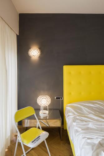 a bedroom with a yellow chair and a bed at Hotel Aurora in Merano