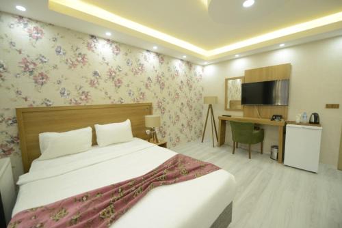 een slaapkamer met een bed en een bureau met een televisie bij ADA LİFE SUİT HOTEL VAN in Bostaniçi