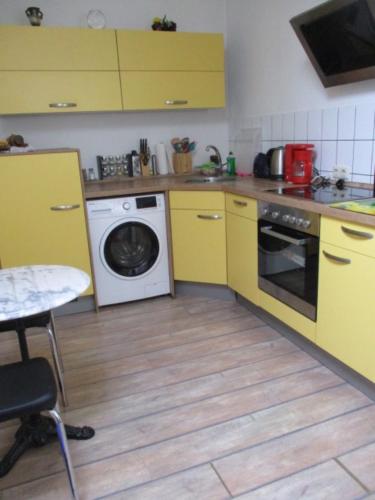 a kitchen with yellow cabinets and a washing machine at Ferienwohnung Thüringer Wald in Ilmenau