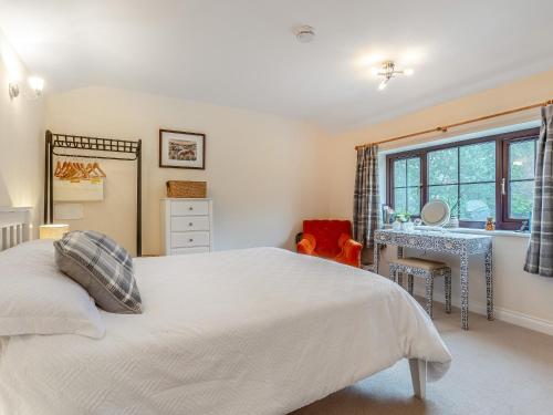 a bedroom with a bed and a desk and a window at The Shippon in Halwill