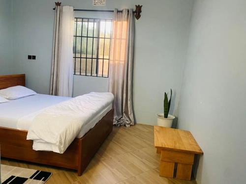 Schlafzimmer mit einem Bett, einem Tisch und einem Fenster in der Unterkunft Venem Ensuite bathroom Elephant house in Kisongo