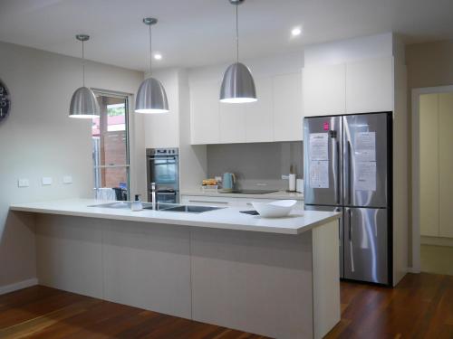 een witte keuken met een wastafel en een koelkast bij Luxury Home in Yowie Bay in Miranda