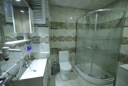 a bathroom with a shower and a toilet and a sink at ADA LİFE SUİT HOTEL VAN in Bostaniçi