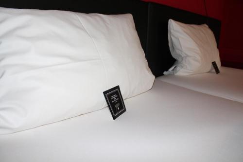 a bed with white pillows with a sign on it at Arthotel ANA Aura in Aystetten