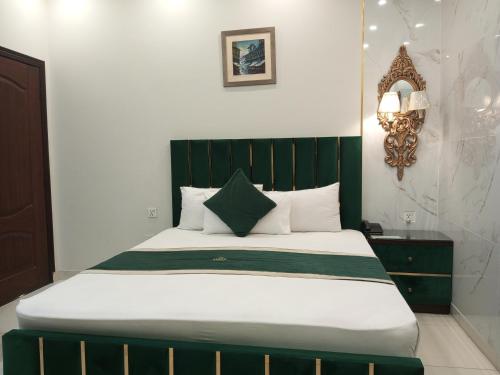 a bed with a green headboard in a room at Golden One Hotel in Lahore