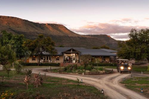 een vrachtwagen die over een onverharde weg rijdt voor een gebouw bij Samara Karoo Reserve in Graaff-Reinet