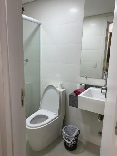 a white bathroom with a toilet and a sink at Apartamento acqua in Pelotas