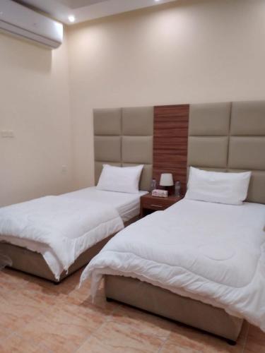 2 camas en una habitación de hotel con sábanas blancas en شقق مساكن ابيات للشقق المخدومة en Al Rass