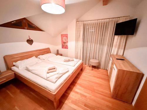 Schlafzimmer mit einem Bett mit weißer Bettwäsche und einem TV in der Unterkunft Modern Mountain Penthouse - an der Skipiste in Rauris