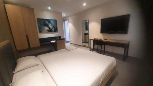 a bedroom with a bed and a desk and a television at Hotel Elite Inn Kolhapur in Kolhapur