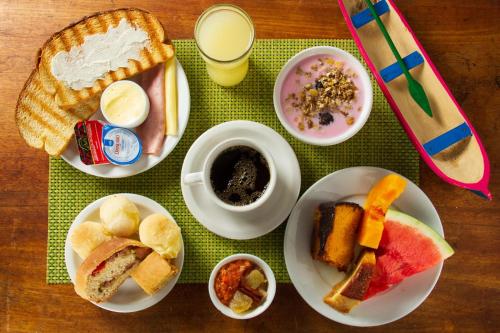a table with plates of breakfast foods and a drink at Pousada Recanto da Ladeira in Paraty