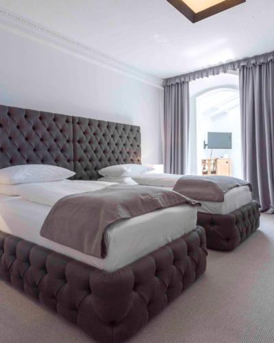 a large bedroom with two beds and a large headboard at Hotel Forstinger - Boutique Hotel Schärding in Schärding