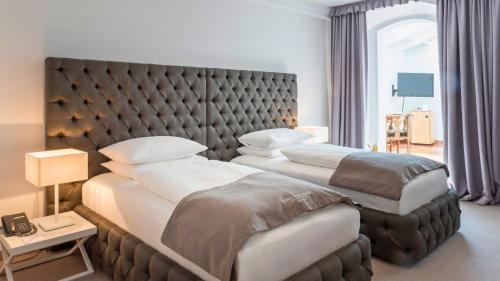 two beds in a hotel room with a headboard at Hotel Forstinger - Boutique Hotel Schärding in Schärding