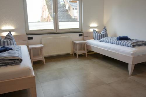 a room with two beds and two windows at Haus Sandkorn in Baltrum