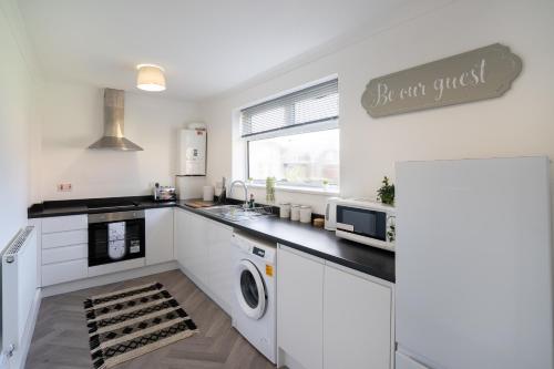 a kitchen with white cabinets and a sink and a microwave at Modern - 2 Bed - Free Parking in Coxhoe