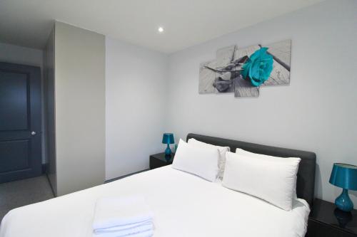 a bedroom with a white bed and a picture on the wall at Barons Court Queens Club by Viridian Apartments in London