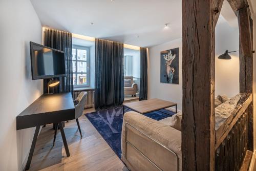 a living room with a couch and a desk with a television at Hotel Forstinger - Boutique Hotel Schärding in Schärding