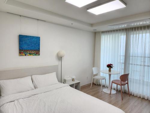 Sokcho Summitbay 1701 "Ocean View" في سوكشو: غرفة نوم بيضاء مع سرير وطاولة