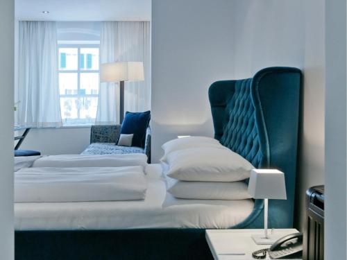 シェルディングにあるHotel Forstinger - Boutique Hotel Schärdingのベッドと椅子付きのホテルルーム