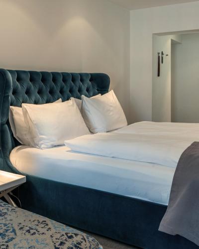 a large bed with a blue headboard and white pillows at Hotel Forstinger - Boutique Hotel Schärding in Schärding