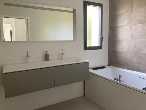 une salle de bain avec une baignoire, un lavabo et un miroir dans l'établissement Villa contemporaine avec piscine, à Sussargues