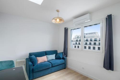 een woonkamer met een blauwe bank en een raam bij 1 Bedroom#Haussmann#Amazing view#EffeilTower#AC in Parijs