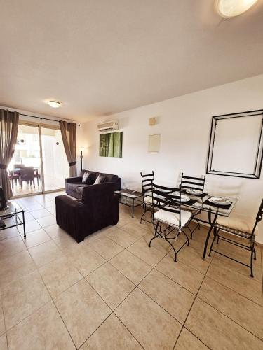 sala de estar con sofá, mesa y sillas en Delightful Poolside apartment, en Pafos