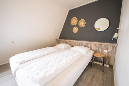 a bedroom with a bed and a table and a mirror at De Berkenhof in Nes