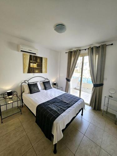 1 dormitorio con cama y ventana grande en Delightful Poolside apartment, en Pafos