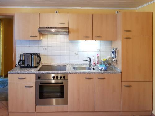 Una cocina con gabinetes de madera y un fregadero. en An der Brake, Bungalow, en Prerow