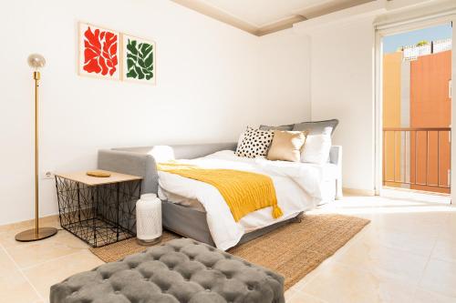 een slaapkamer met een bed en een poef bij Apartamento coqueto con terraza junto a Candelaria in Candelaria
