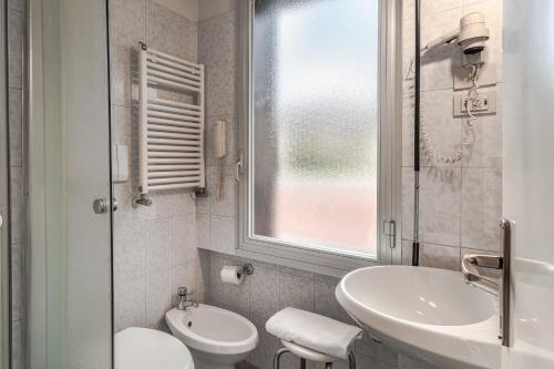 a bathroom with a sink and a toilet and a window at Hotel La Capannina in Genova