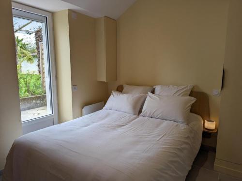 un lit blanc dans une chambre avec une fenêtre dans l'établissement Studio confort à Angoulême avec terrasse, proche transports, idéale pour couples et bébés. - FR-1-653-231, à Angoulême