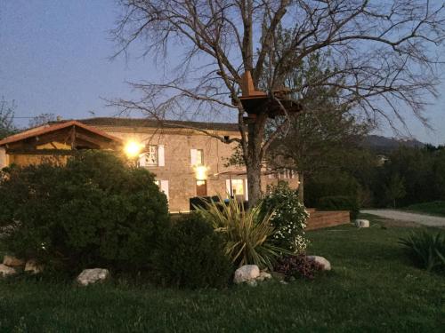 a house with a birdhouse on a tree in a yard at Agréable bastide provençale avec piscine in Barcelonne