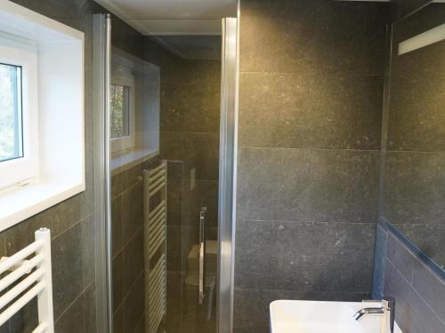 a bathroom with a toilet and a glass shower at Forest-View Tiny House in Hoenderloo