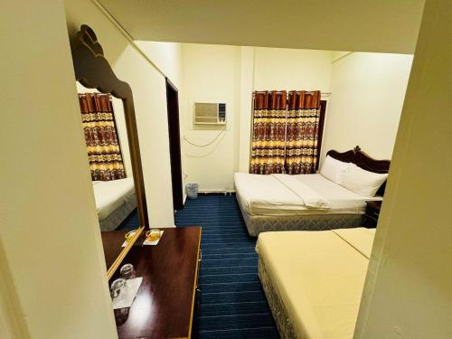 una camera d'albergo con due letti e uno specchio di Al Wehda Hotel a Dubai