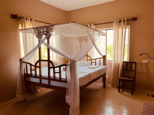 a bedroom with a canopy bed and a window at Binta Boutique Hotel in Nungwi