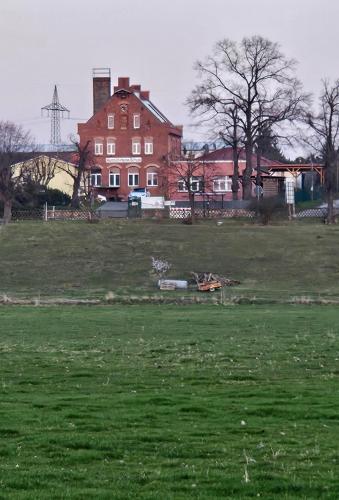 a large field with a large red house in the background at Gästehaus Heinrich Heine Schule in Bad Dürrenberg