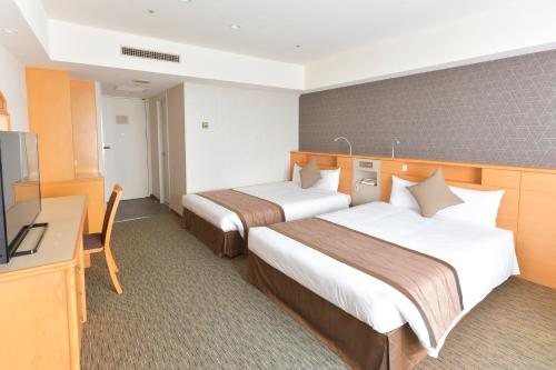 a hotel room with two beds and a flat screen tv at Narita Tobu Hotel Airport in Narita