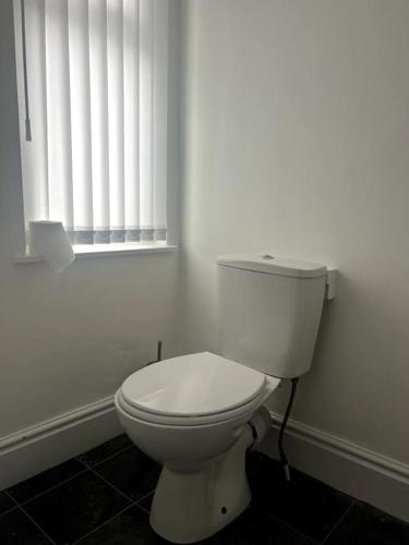 a white toilet in a bathroom with a window at No. 10 - Home away from Home in Litherland