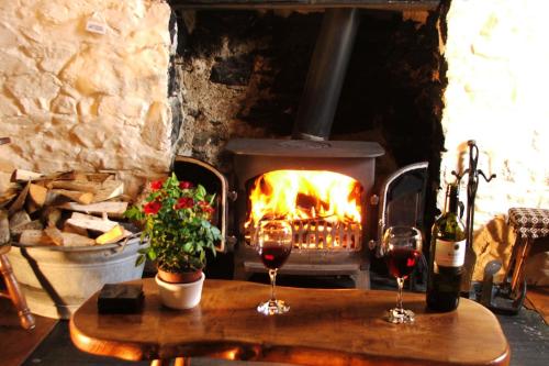 two glasses of wine on a table in front of a fireplace at Bryn-y-Gof Llangrannog in Blaencelyn