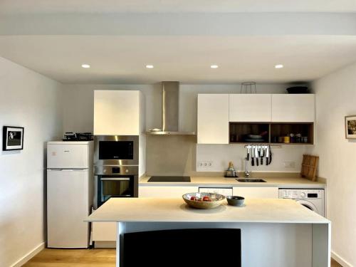 una cocina con armarios blancos y un bol de fruta en una barra en Appartement vue sur golf Son Parc Menorca, en Son Parc