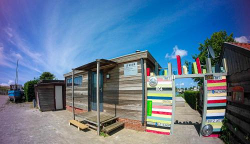 a small house with a sign in front of it at Chalet Valentina directly on the Lauwersmeer in Anjum