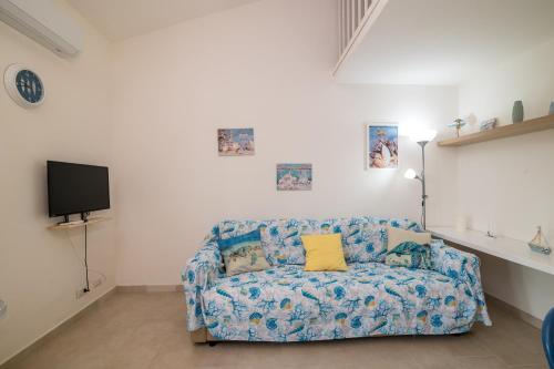 a living room with a blue couch and a tv at Le Dimore Ibiscus in Stintino